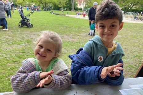 Two small children smiling widely while rolling seed bombs in their hands